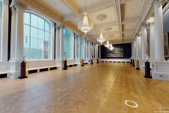 A long Gallery with chandeliers, polished wooden floors, and large windows at one side.
