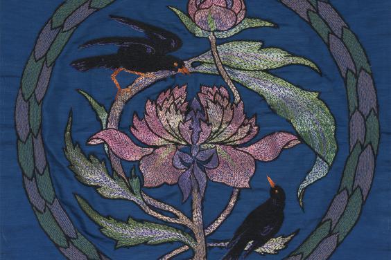 An embroidered cushion cover featuring a design with blackbirds and peonies