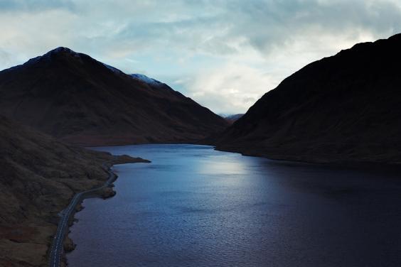 A still from a documentary film, showing a lake surrounded by mountains