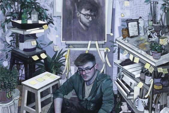View of an artist's studio with a man wearing glasses seated on the floor in front of an easel with a self-portrait. Artist materials and sketches and plants surround him.