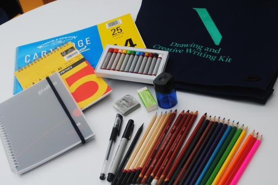 The contents of a drawing and creative writing kit including sketch pads, pencils, colouring pencils, oil pastels, eraser, sharpener, black pen and marker