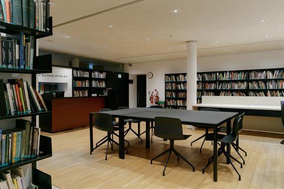 Photo of an empty room. The walls are lined with bookshelves and there is a large table in the centre of the room.