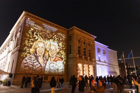 Merrion Square facade of the National Gallery of Ireland building with a portrait of two smiling people projected on to the facade