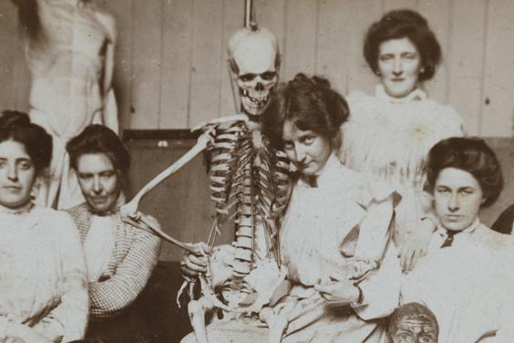 Vintage black and white photo of women posing with a medical skeleton model