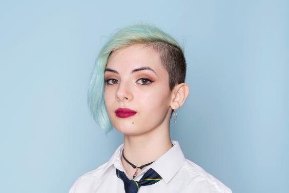Colour photograph portrait by artist Mandy O'Neill showing teenage girl in school uniform against a pale blue background.
