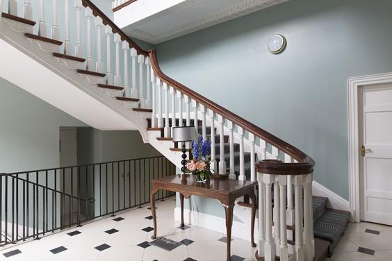 Grand staircase in a light blue room with black and white tiles