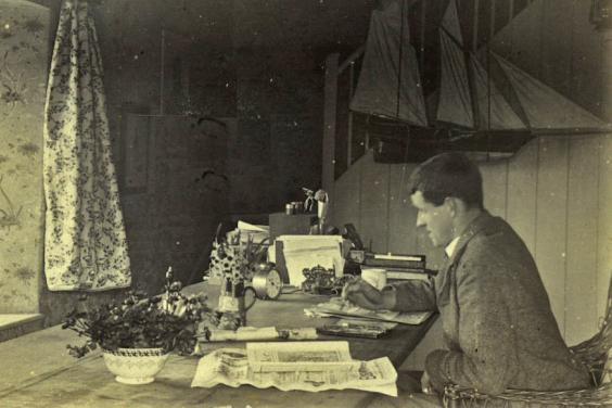 Jack B Yeats sits at his desk working - in front of him, standing on the window sill and looking directly at the camera is his dog HooliganGallery of Ireland's Yeats Archives