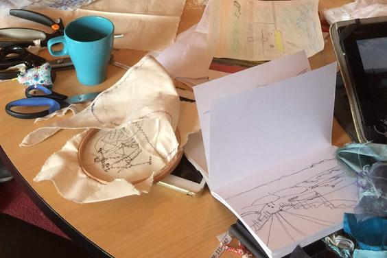 Photo of a table covered in craft materials and textiles.