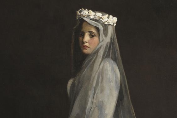 Portrait of a young girl wearing a white communion dress, headdress and veil.