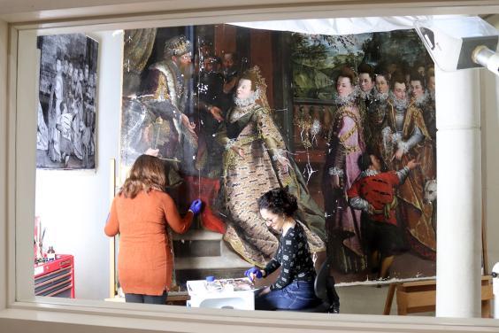 A window into the conservation studio showing conservators at work on Lavinia Fontana's painting