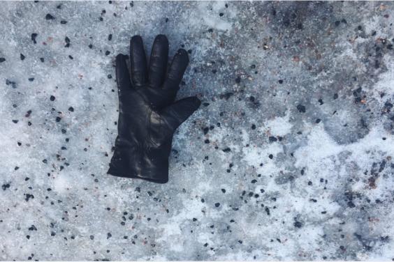 Photo of a black glove lying on a grey stone surface.