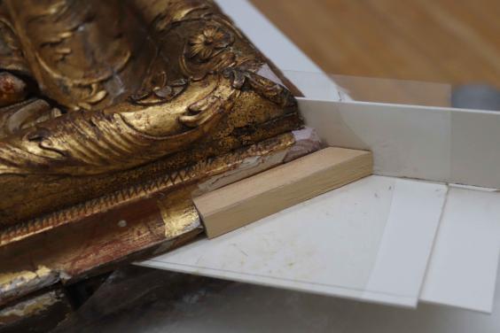 Broken corner of gilded picture frame being repaired with a wooden insert