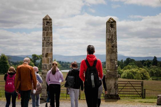 Group of young people walking towards a gate with stone pillars