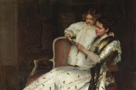 A woman in a long full-skirted white dress with small rosettes on it reclines on a chair. Standing beside her with her hand around her neck is a small child, also in white. They are both reading a book together.