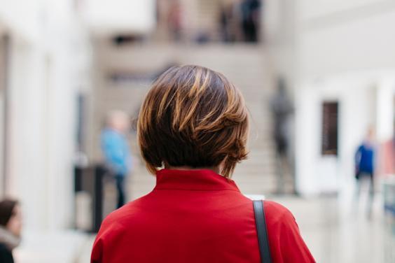 Photo of a woman with her back to the camera, wearing a red coat, standing in the lobby of the Millennium Wing of the National Gallery of Ireland.