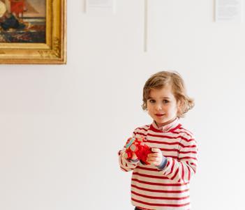 A child standing in front of a gold-framed painting in the Gallery