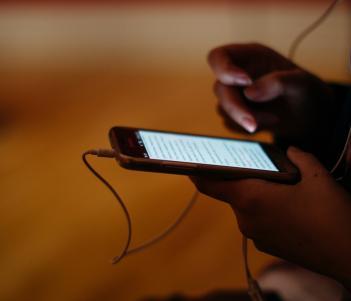 Someone holding a phone in their hands with headphones attached