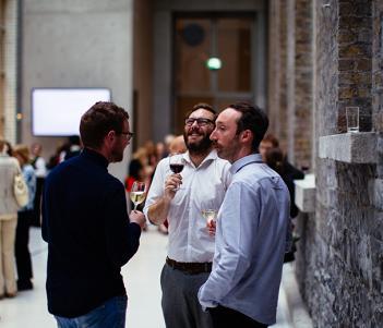 Three men drinking wine at an event