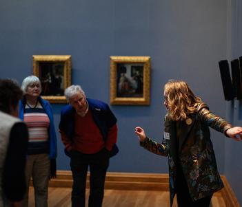 Photo of a tour guide speaking to a group of visitors in front of Dutch seventeenth-century paintings in the National Gallery of Ireland.