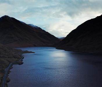 A still from a documentary film, showing a lake surrounded by mountains
