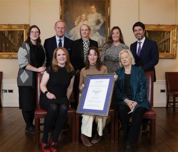 Photograph of a group of eight people in a grand room