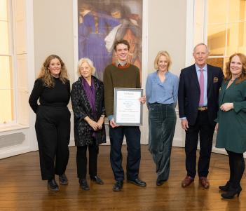 Photograph of a group of six adults, on holding a framed certificate