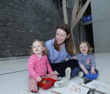Photograph of a young woman in a blue top with two toddlers
