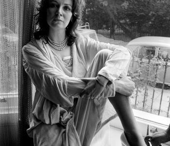 Black and white photograph of a woman sitting with her leg up on a windowsill.