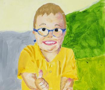 A portrait of a young boy in a yellow t-shirt and blue glasses. He is smiling and has both hands outstretched with his thumbs up.s