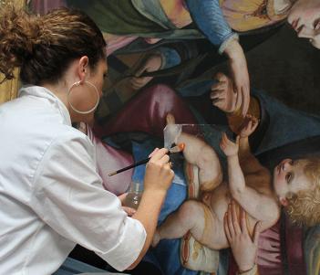 A conservator working on an oil painting