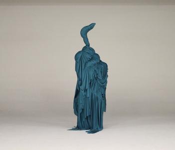 Teal-coloured sculptural costume made from draped cloth and resembling a bird with a long neck