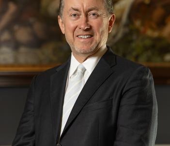 A man in a suit with a white tie in front of a painting