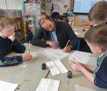 An artist drawing with three school students in a Your Gallery at School workshop
