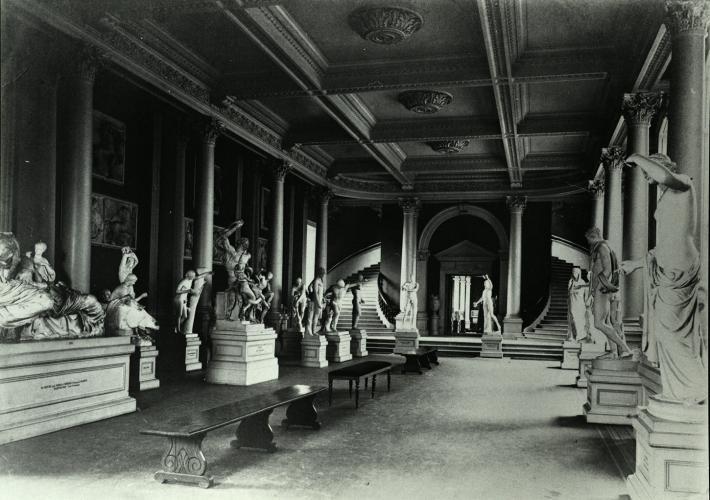 A black and white photograph of a large gallery space, filled with plaster casts.